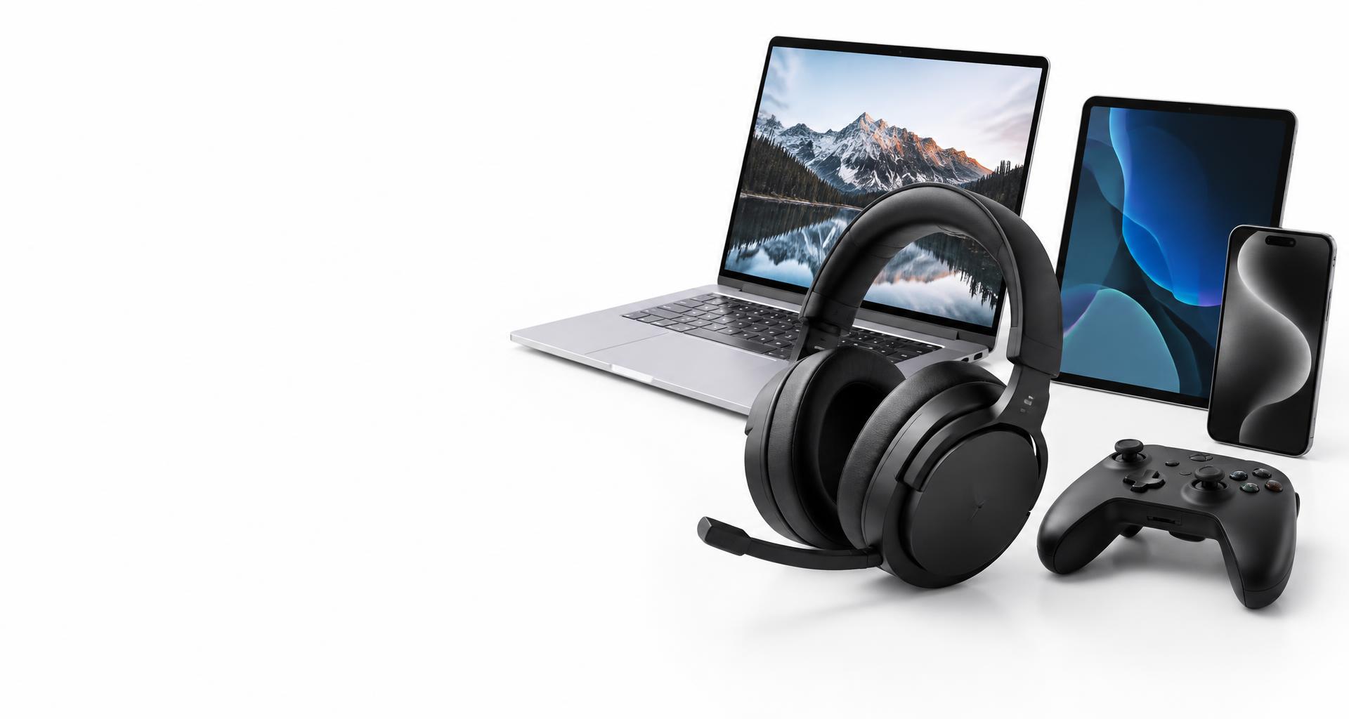 Headset, laptop, tablet, phone and gaming controller on a bright white surface